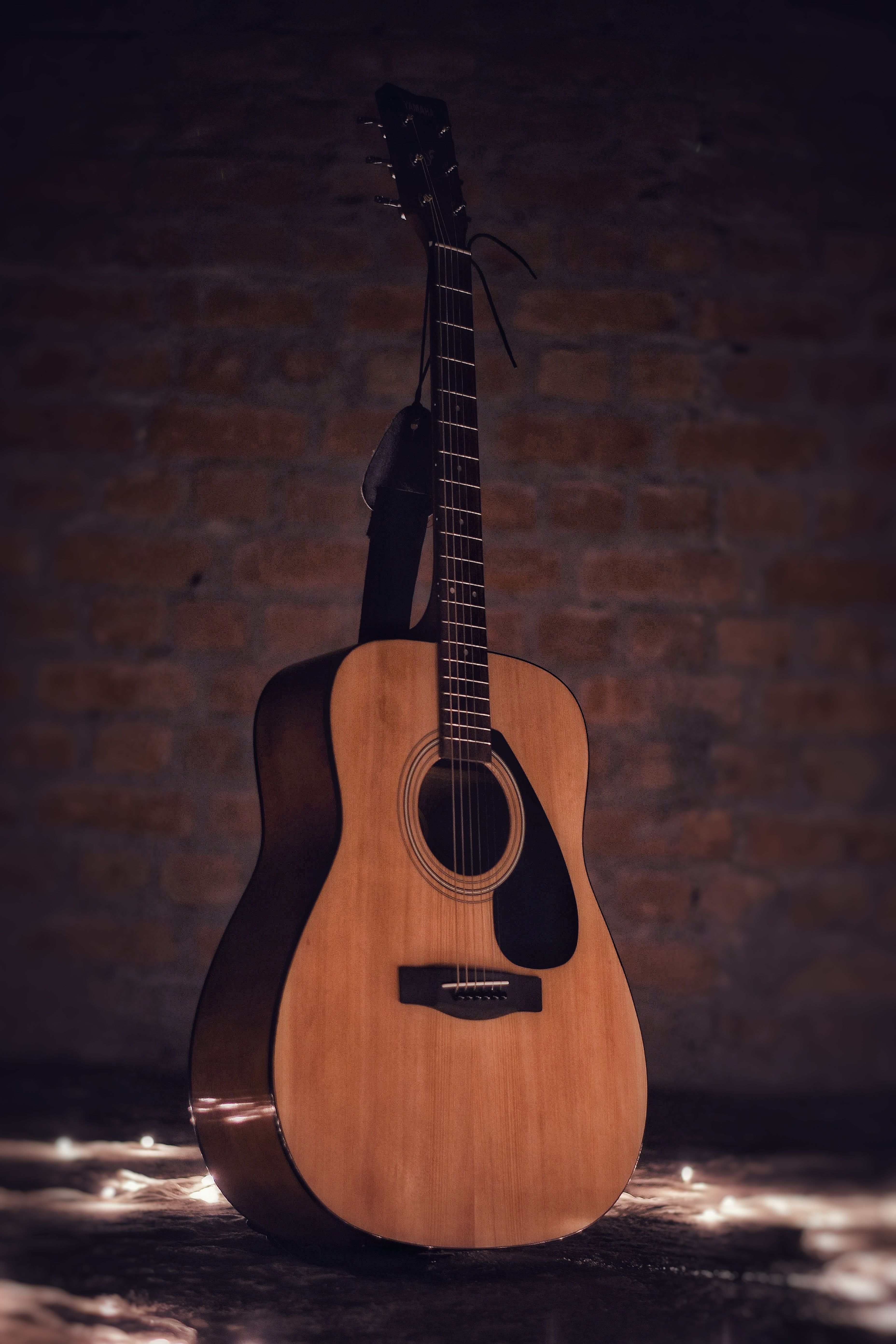 Stock photo — an acoustic guitar hanging on a brick wall (placeholder; swap for real Intentional Studios photography)