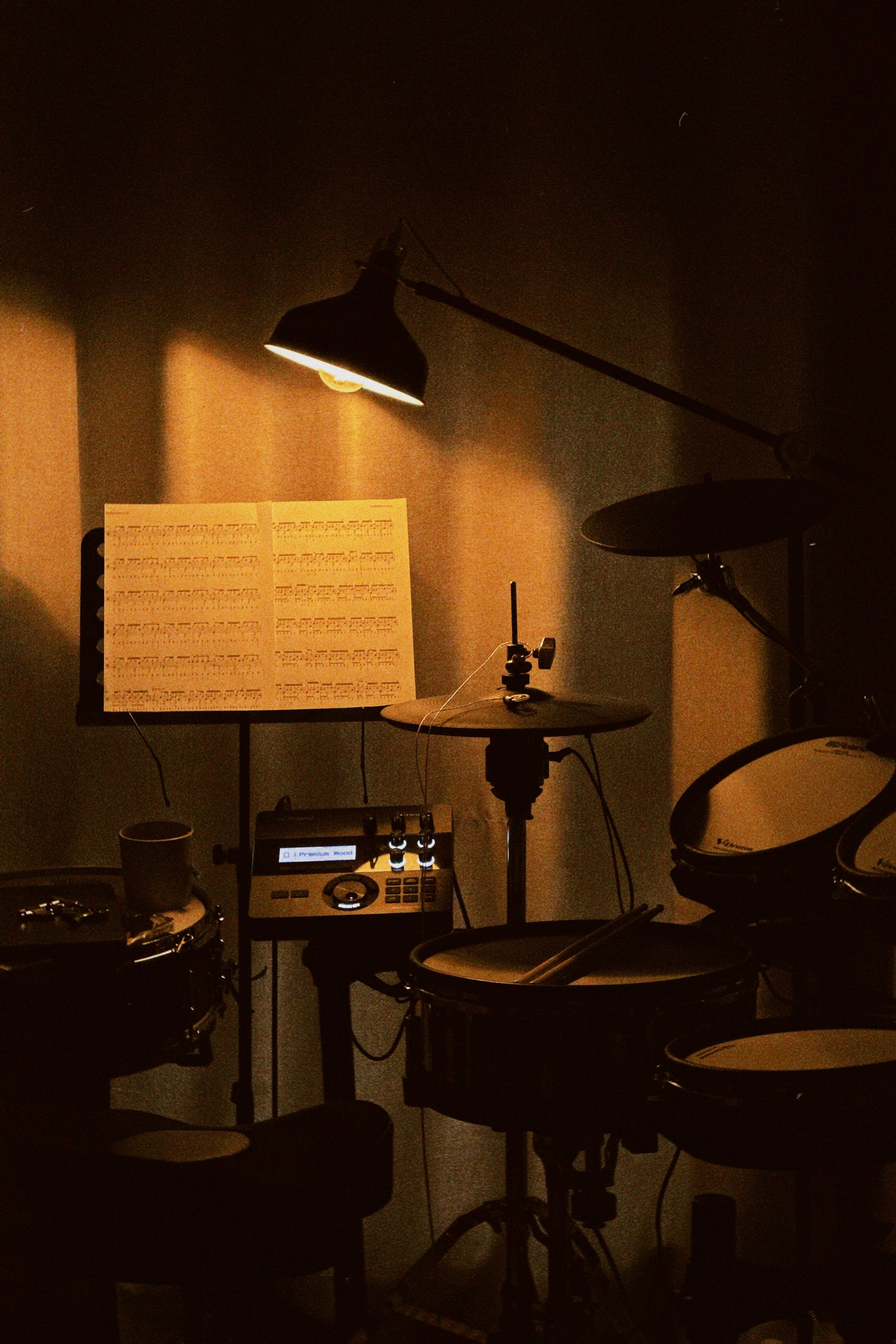 Stock photo — a drum kit with sheet music under a warm desk lamp (placeholder; swap for real Intentional Studios photography)